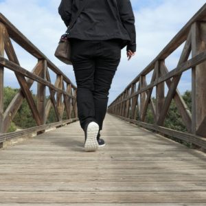 Rückansicht laufende Person auf Holzbrücke